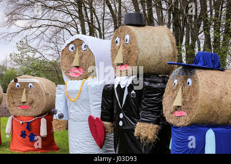 Giant famiglia di agricoltori burattini (paglia bambole) realizzato al di fuori della balla di fieno. Coppie in viaggio di nozze con i suoi bambini in un campo di una fattoria vicino a Gescher, Germania Foto Stock