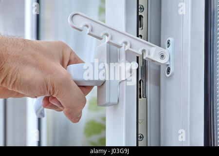 Close-up, la mano apre la finestra in PVC tirando la maniglia dotata di un limitatore di finestra. Foto Stock