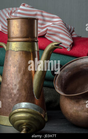 Vuoto in rame e bronzo bovini di tè e pot con diversi colori di sfondo di stoffa. Foto Stock