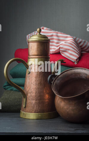 Vuoto in rame e bronzo bovini di tè e pot con diversi colori di sfondo di stoffa. Foto Stock