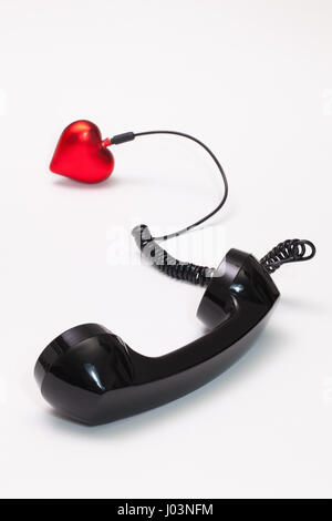 Vecchio ricevitore telefonico e cavo collegamento con cuore rosso. Amore concetto hotline. Foto Stock