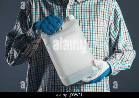 Irriconoscibile agricoltore maschio con marcato del serbatoio di plastica barattolo contenente pesticidi per impianto di trasformazione in agricoltura Foto Stock