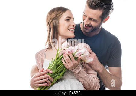 Giovane uomo abbracciando la donna incinta che holding bouquet di tulipani freschi Foto Stock