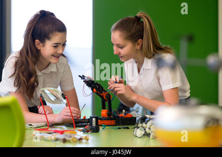 Due studenti di sesso femminile stanno lavorando insieme nella scuola per costruire il corretto funzionamento di un braccio robotico. Foto Stock