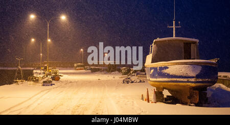 La neve cade su una barca e mare parete sotto l illuminazione notturna a Helmsdale Porto di Sutherland nel lontano Nord delle Highlands della Scozia. Foto Stock