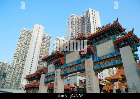 Ornati in cinese tradizionale Gateway contrasta con la Skyline di Kowloon all'Wong Tai Sin Temple, Hong Kong. Foto Stock