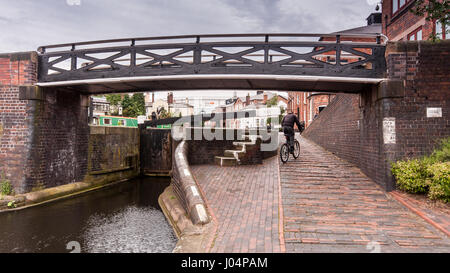 Birmingham, Inghilterra, Regno Unito - 23 Giugno 2012: Un ciclista corse su strada alzaia del Birmingham e Fazeley Canal, passato ponti e blocca in Birmingham City Foto Stock