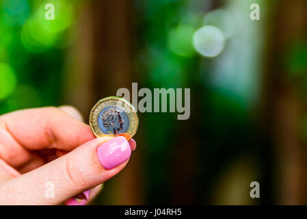 Femmina di mano azienda new british uno sterling pound coin. Foto Stock