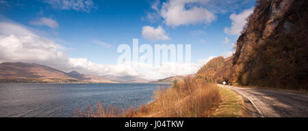 Un singolo paese via strada corre sotto le scogliere sulle rive di Loch Carron, un ingresso del mare del nord-ovest Highlands della Scozia. Foto Stock