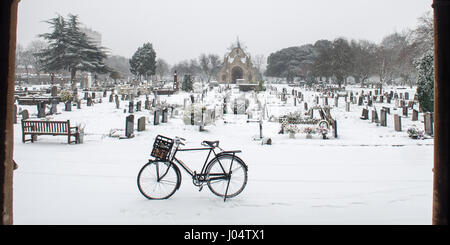 Un tradizionale inglese bicicletta montante sorge nella neve a Lambeth nel cimitero Tooting, a sud-ovest di Londra. Foto Stock