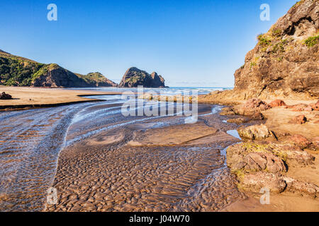 Piha Beach a bassa marea, con trama profondamente la sabbia nel letto di ruscello. Foto Stock