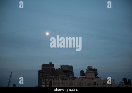 La luna piena sorge sopra i vecchi edifici industriali del Nord del Tribeca a Manhattan, New York City. Il 9 aprile 2017 Foto Stock