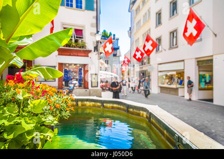 Centro storico della città di Zurigo con Swiss bandiere pendenti da edifici con sfondo bokeh effetto di sfocatura in una giornata di sole in estate, Svizzera Foto Stock