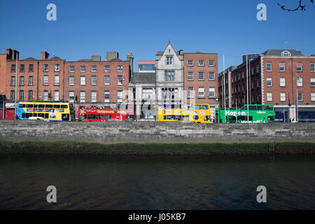 Gli autobus turistici allineati lungo il fiume Liffey nella città di Dublino, Irlanda. Foto Stock