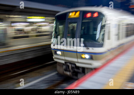 Unfocused treno arriva alla stazione ferroviaria di Tokyo, Giappone Foto Stock