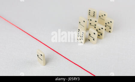 Espulso dal gruppo, incapace di attraversare la linea rossa che li separa. In scena con gruppo di domino. Concetto di accusa colpevole, bulling o emarginati nel team. Sfondo chiaro Foto Stock