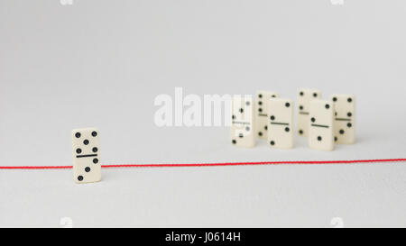 Espulso dal gruppo, incapace di attraversare la linea rossa che li separa. In scena con gruppo di domino. Concetto di accusa colpevole, bulling o emarginati nel team. Sfondo chiaro Foto Stock