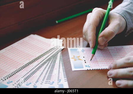 WROCLAW, Polonia - Marzo 28th, 2017: uomo di compilare un lotto di biglietti della lotteria. Lotteria organizzata da TOTALIZATOR SPORTOWY. Esso è stato in Polonia dal 1957. Foto Stock