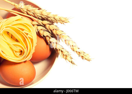 Uova di gallina con frumento spikelets e pasta isolati su sfondo bianco tonica Foto Stock