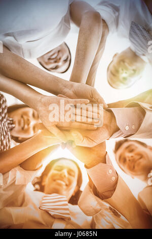 Direttamente sotto il ritratto la gente di affari di impilamento mentre le mani in piedi in ufficio Foto Stock