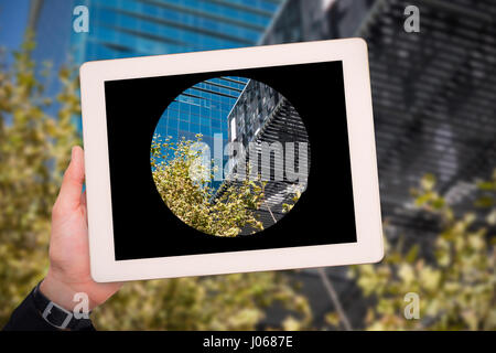 Mano maschile tenendo contro della compressa a basso angolo di visione degli edifici moderni Foto Stock