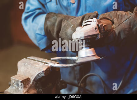 Realizzazione di ferro di cavallo. Lavoratore di sesso maschile a ferro di cavallo di lucidatura. Foto Stock