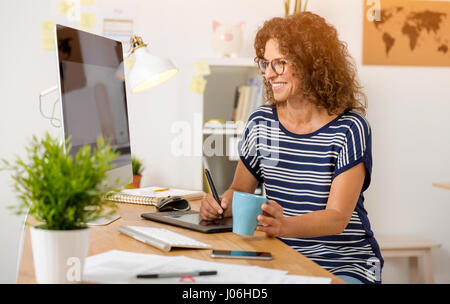 Età media designer che lavora su un desktop con una penna stilo Foto Stock