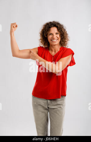 Ritratto di un sorridente di mezza età brunette rivolta verso il suo muscolo del braccio Foto Stock