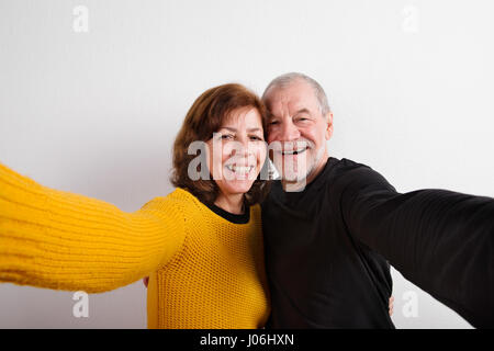 Coppia senior in amore abbracciando, tenendo selfie. Studio shot. Foto Stock