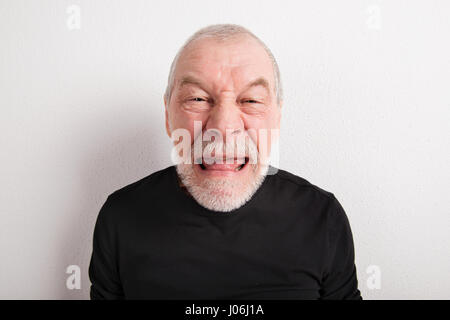 Senior uomo rendere divertente faccia, studio shot. Foto Stock