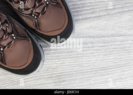 Nuove scarpe da trekking su sfondo di legno dal di sopra. Nuove scarpe marrone su bianco sullo sfondo di legno closeup. Calzature con sfondo copy-spazio su ba in legno Foto Stock