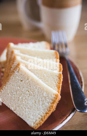 Torta madeira sulla piastra con una tazza di tè, burro pan di spagna Foto Stock