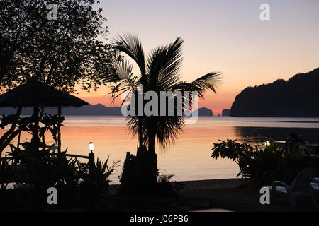 Godersi la fine del t egli giorno in un piccolo resort direttamente sulla spiaggia di El Nido Foto Stock