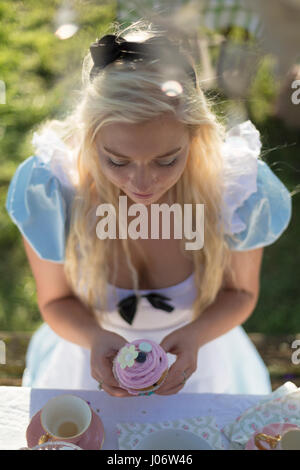 Giovane donna vestita come Alice nel Paese delle Meraviglie con grande carta  da gioco e fiori Foto stock - Alamy