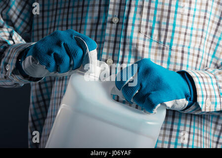 Irriconoscibile agricoltore maschio con marcato del serbatoio di plastica barattolo contenente pesticidi per impianto di trasformazione in agricoltura Foto Stock