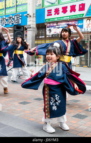 Giapponese Hinokuni Yosakoi dance festival. Il team di danza in blu scuro yukata con un bambino piccolo, ragazza, 4-5 anni, davanti a ballare. Foto Stock