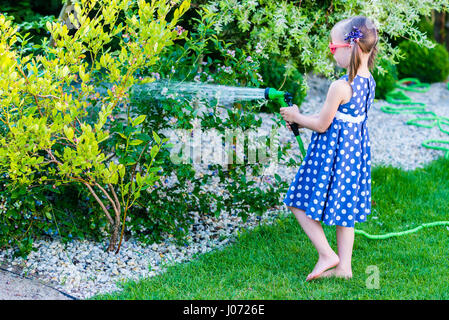 Poco felice ragazza di irrigazione - giardino cespugli di mirtilli Foto Stock