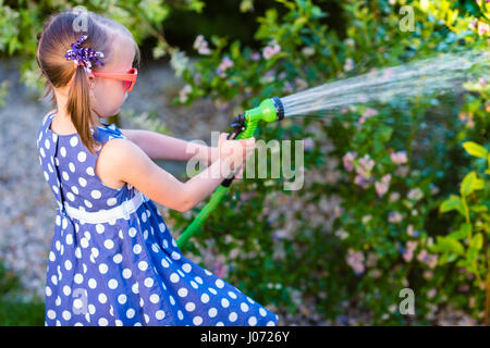 Poco felice ragazza di irrigazione - giardino cespugli di mirtilli Foto Stock