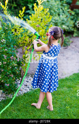 Poco felice ragazza di irrigazione - giardino cespugli di mirtilli Foto Stock