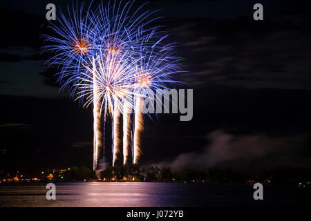 Fuochi d'artificio celebrazione blu e oro riflettente nel lago Foto Stock