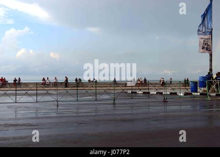 La gente del posto seduto a guardare il mare sul Malecon in serata, Havana Cuba Foto Stock