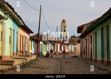 Una vista su una strada a ciottoli del piano singolo case colorate verso il campanile di Trinidad di Cuba Foto Stock