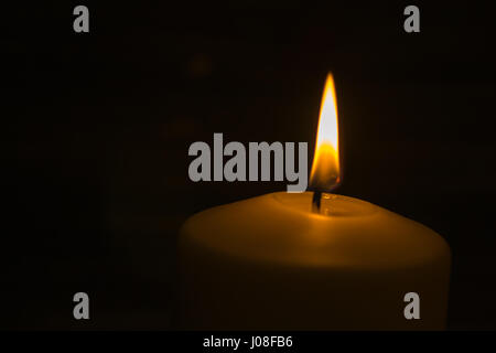 Una candela è accesa nelle tenebre e dà calore spirituale Foto Stock