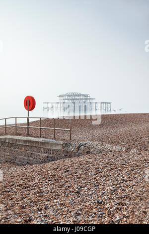 La spiaggia di Brighton e i resti del vecchio molo Ovest su un nebbioso giorno in luce piatta, Sussex, Inghilterra, Regno Unito. Foto Stock
