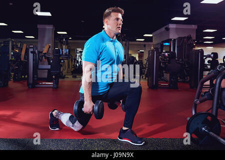 Atleta con manubri facendo esercizi squats in palestra Foto Stock