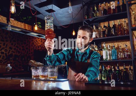 Il barman versa l'alcol in un bicchiere Foto Stock