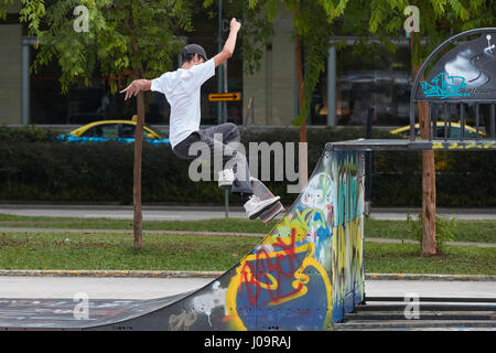 Giovane uomo asiatico lo skateboard in scape skate park, Singapore. Foto Stock