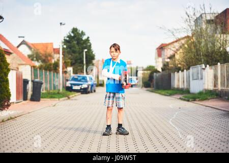 Maliziosa ragazzo con mano rotto infortunato dopo incidente su skateboard. Foto Stock