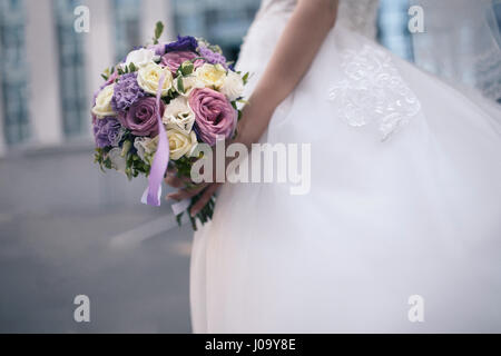 Un matrimonio bouquet di viola e fiori bianchi nelle mani della sposa. La foto in orizzontale Foto Stock