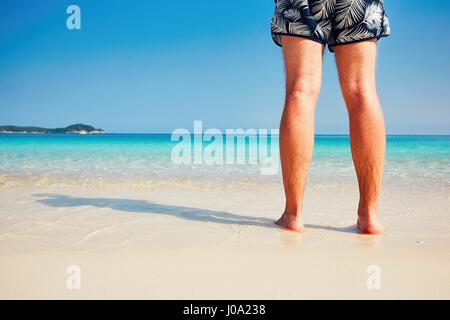 Le gambe del giovane in vacanza. Spiaggia idilliaca sulle isole Perhentian in Malesia. Foto Stock